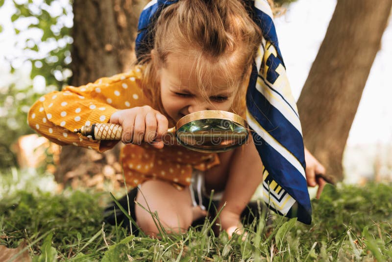 Afbeelding van een schattig kind met vergrootglas dat de natuur in de openlucht verkent Verachtelijk klein meisje dat in het bos