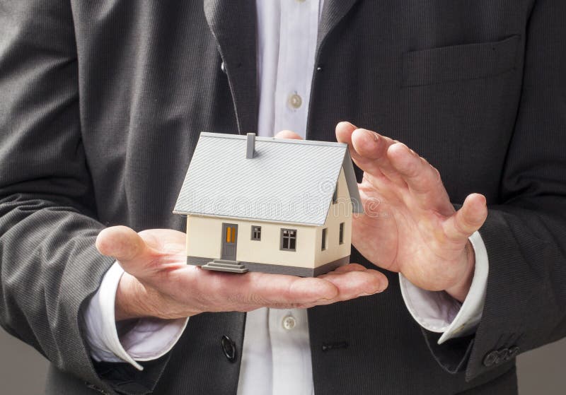 Affaires d'agent d'agent immobilier avec la maison dans des mains