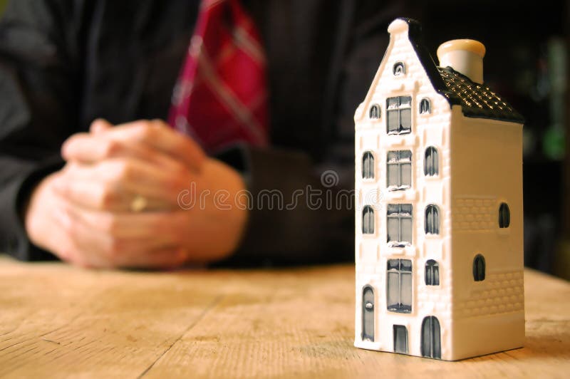 A businessman sits in the background of a model property. A businessman sits in the background of a model property.