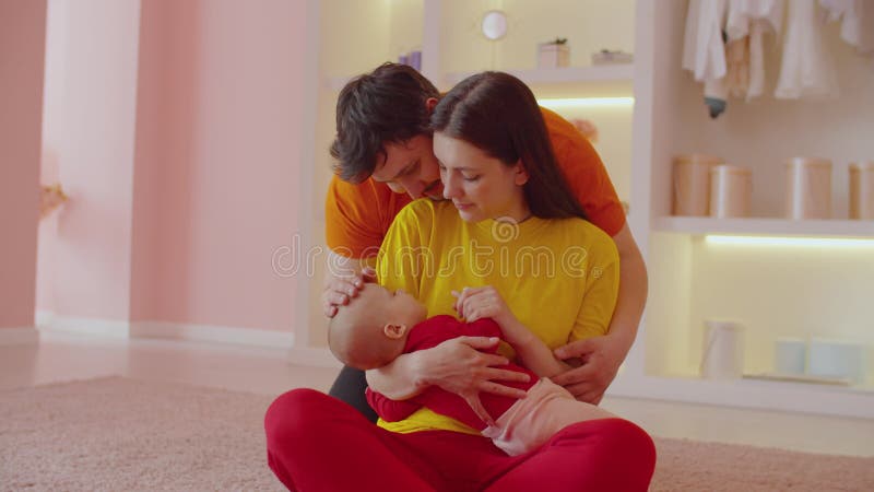 Affectionate caring parents with sleeping infant child bonding at home.