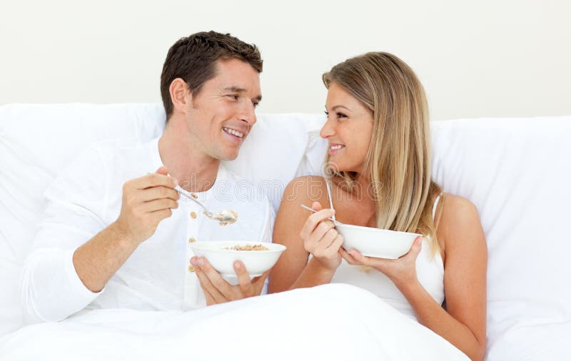 Affectionate couple having breakfast lying on their bed. Concept of love. Affectionate couple having breakfast lying on their bed. Concept of love.