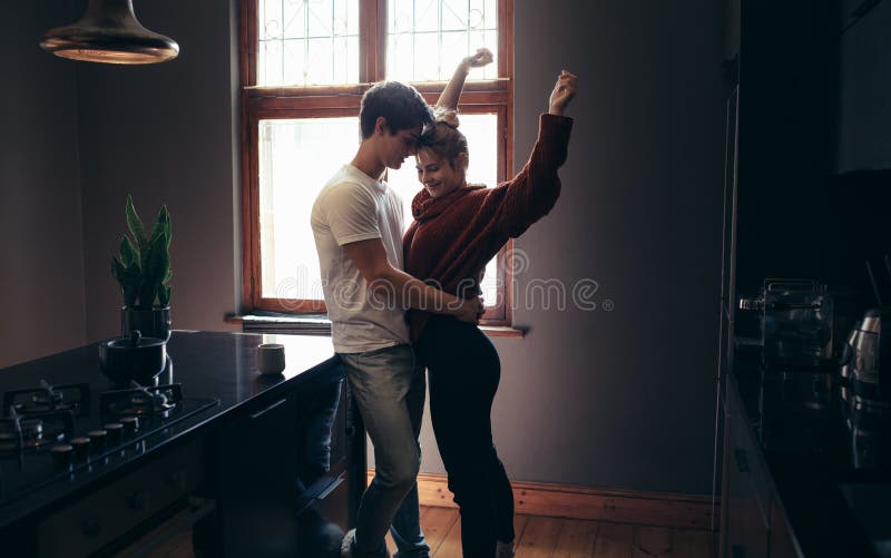 Affectionate couple standing together in the kitchen stock images