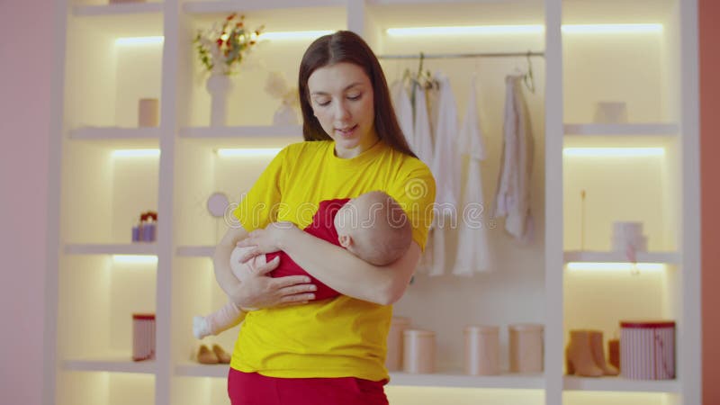 Affectionate pretty mother rocking cute infant baby to sleep indoors