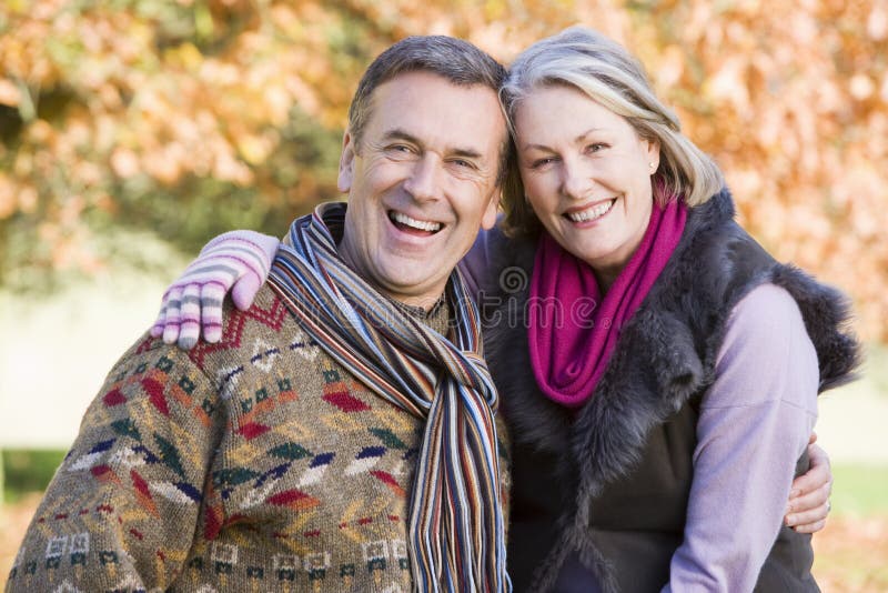 Affectionate senior couple on autumn walk with trees in background