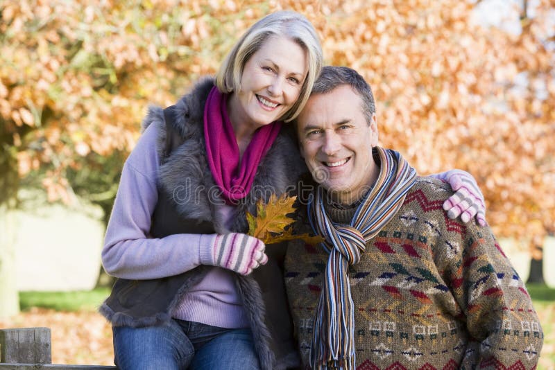 Affectionate senior couple on autumn walk with trees in background