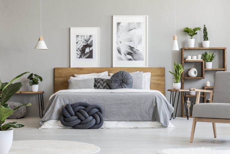 Affiches boven houten bed in grijs slaapkamerbinnenland met installaties royalty-vrije stock fotografie Affiches boven houten bed in grijs slaapkamerbinnenland met installaties royalty-vrije stock fotografie