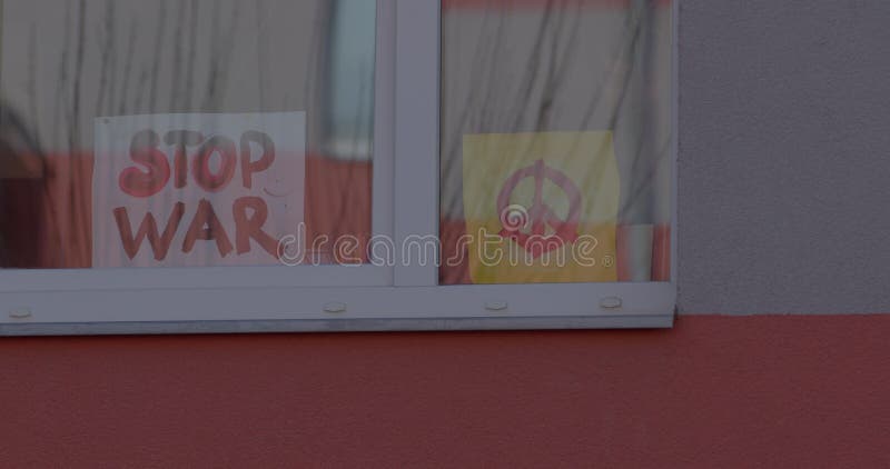 Affischer stoppar kriget i husets fönster. symboler för fredsduva och olivgrenen.