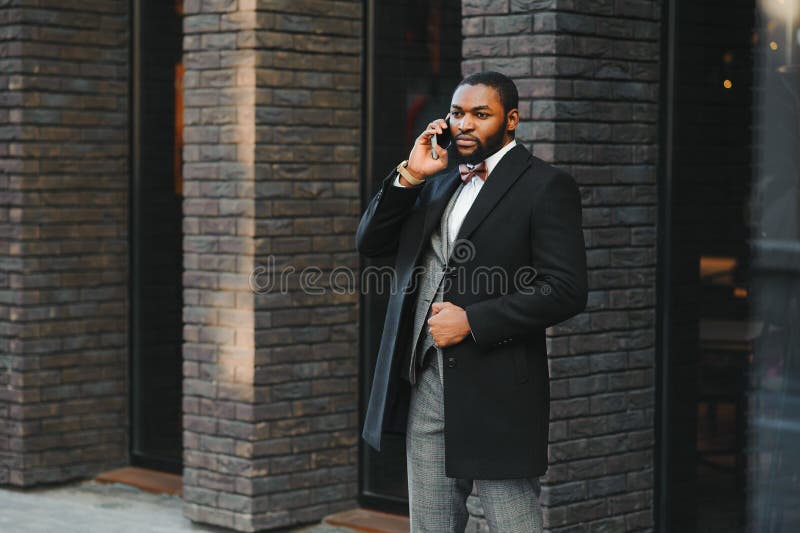 Affärskommunikation. lycklig ung afrikan-man på formella kläder som pratar på mobiltelefon och leende medan han står utomhus arkivfoto