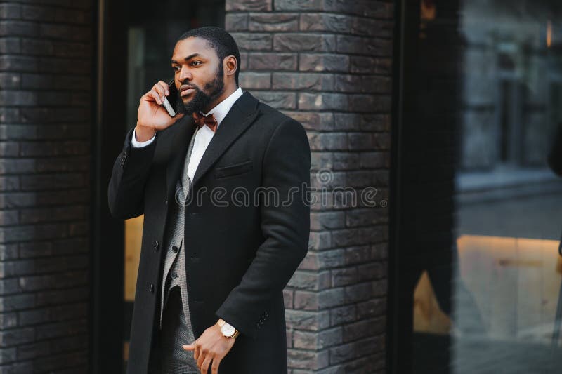 Affärskommunikation. lycklig ung afrikan-man på formella kläder som pratar på mobiltelefon och leende medan han står utomhus royaltyfri foto