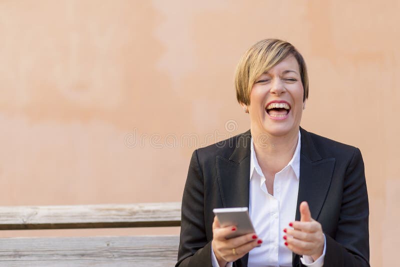 Affärskvinna som förestående ler med en mobiltelefon royaltyfria bilder Affärskvinna som förestående ler med en mobiltelefon royaltyfria bilder