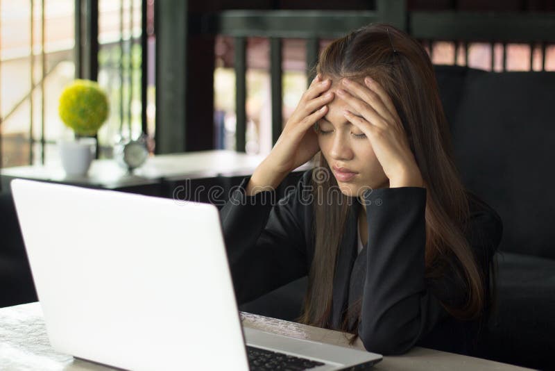 Affärskvinna som har huvudvärk, medan arbeta genom att använda bärbara datorn Comput