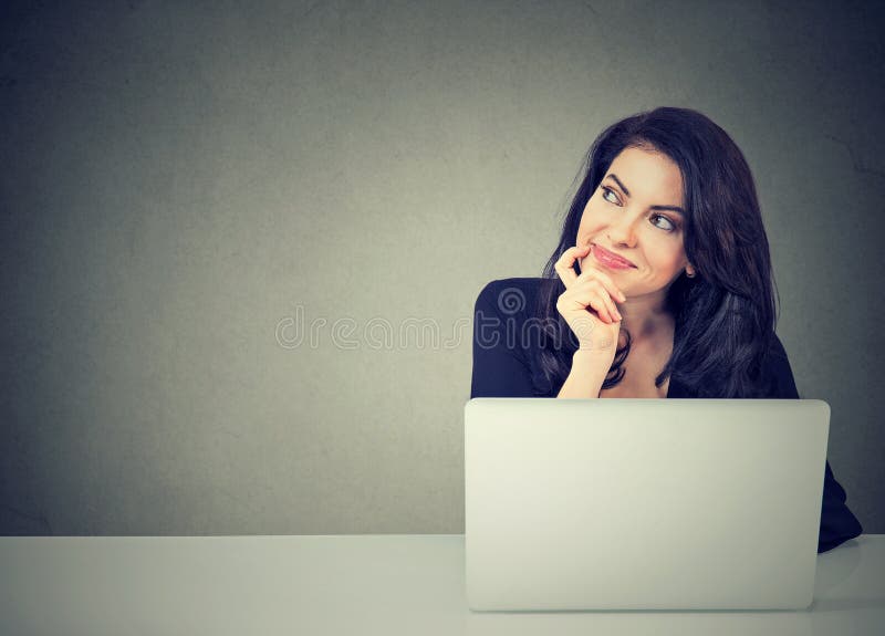Affärskvinna som tänker dagdrömma sammanträde på skrivbordet med bärbar datordatoren