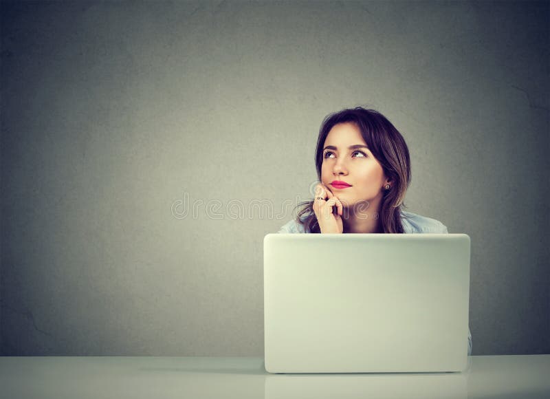 Affärskvinna som tänker dagdrömma sammanträde på skrivbordet med bärbar datordatoren
