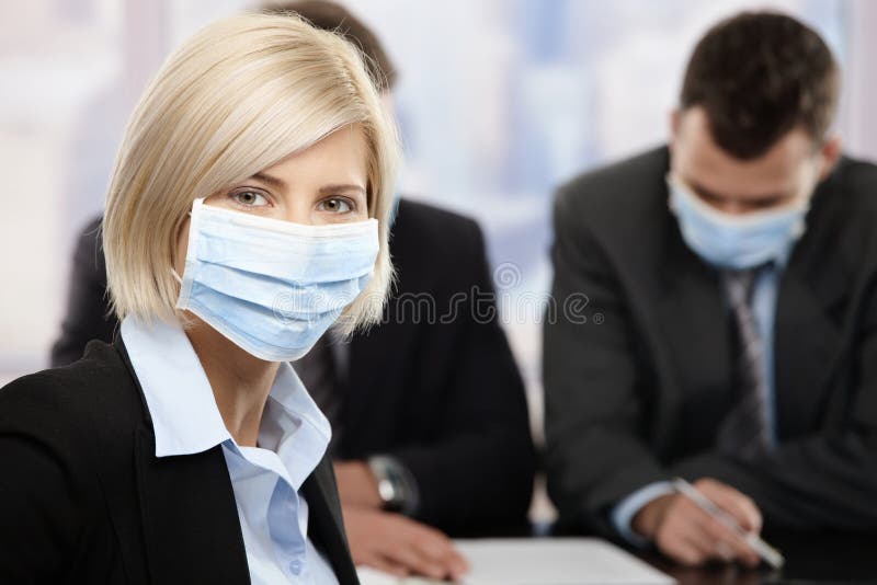 Businesswoman fearing h1n1 swine flu virus wearing protective face mask during meeting at office. Businesswoman fearing h1n1 swine flu virus wearing protective face mask during meeting at office.