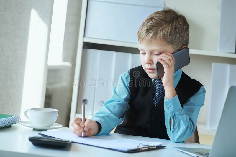 Affärsman chef som antecknar och pratar på telefonen som sitter vid skrivbordet med en bärbar dator på kontoret royaltyfri fotografi