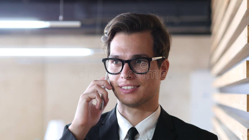 Affärsman i dräkt som talar på Smartphone, att le och att koppla av arkivfoto Affärsman i dräkt som talar på Smartphone, att le och att koppla av arkivfoto