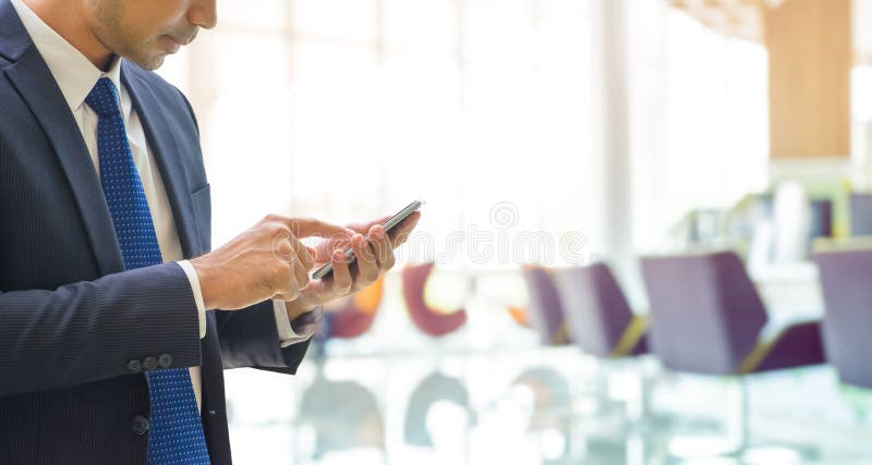 Affärsman som använder mobiltelefonen med bakgrund för suddighetsbankkontor royaltyfri foto Affärsman som använder mobiltelefonen med bakgrund för suddighetsbankkontor royaltyfri foto
