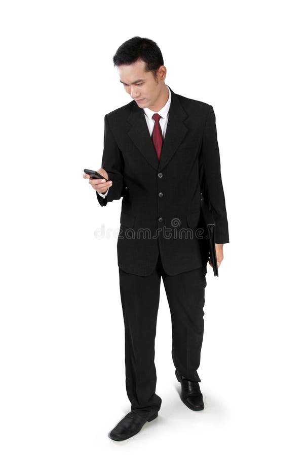 Affärsman som går och att kontrollera på telefonen arkivbild Affärsman som går och att kontrollera på telefonen arkivbild