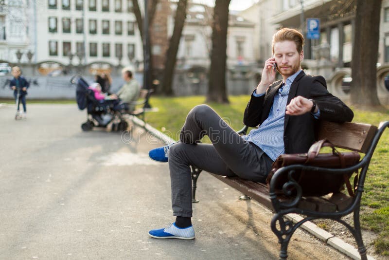 Affärsman som kontrollerar tiden som ser hans klocka på en solig da royaltyfri fotografi Affärsman som kontrollerar tiden som ser hans klocka på en solig da royaltyfri fotografi