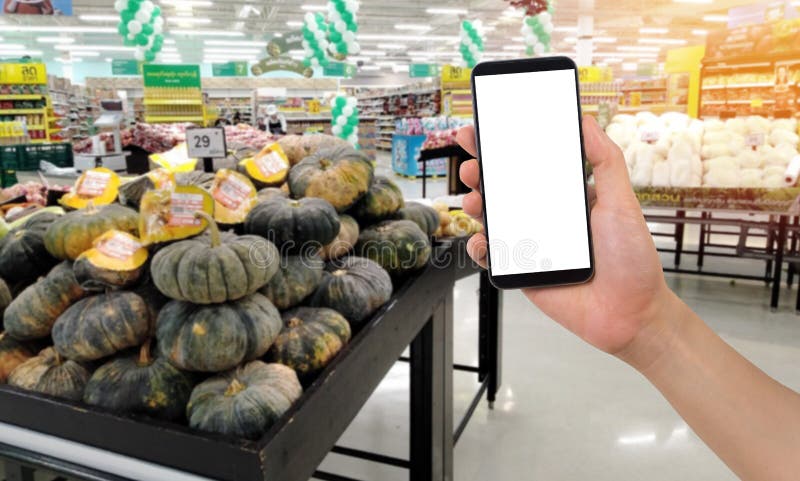 Affärsman som rymmer den tomma skärmen för text på smartphonen, mobil, mobiltelefon med oskarp pumpafrukt på hyllabakgrund royaltyfria foton Affärsman som rymmer den tomma skärmen för text på smartphonen, mobil, mobiltelefon med oskarp pumpafrukt på hyllabakgrund royaltyfria foton