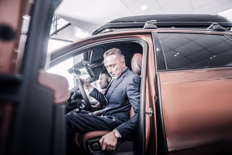 Affärsman som tillbaka skjuter hans plats, medan sitta i ny bil royaltyfri fotografi Affärsman som tillbaka skjuter hans plats, medan sitta i ny bil royaltyfri fotografi