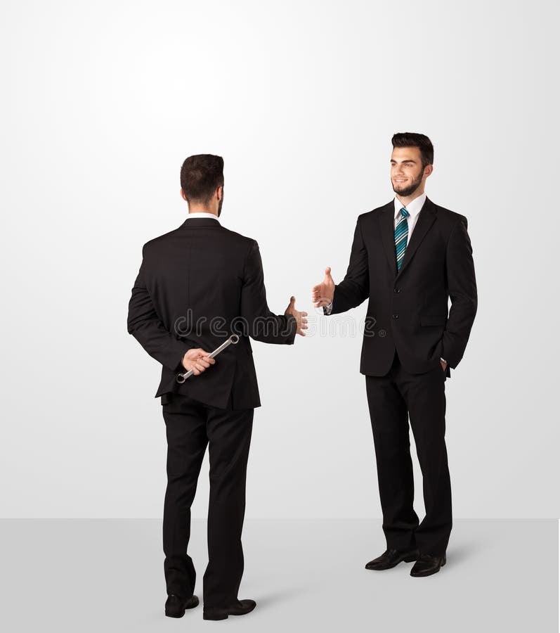Two opposing businessman shake hands, one of them hiding a weapon behind his back. Two opposing businessman shake hands, one of them hiding a weapon behind his back