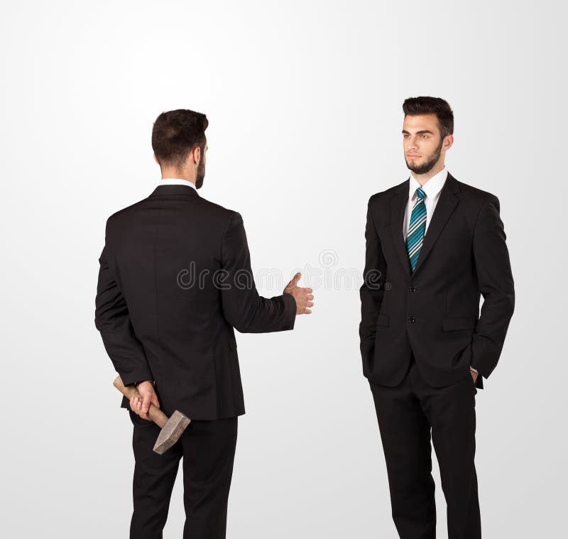 Two opposing businessman shake hands, one of them hiding a weapon behind his back. Two opposing businessman shake hands, one of them hiding a weapon behind his back