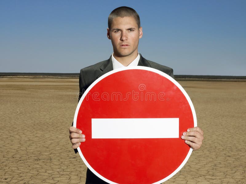 Portrait of young businessman holding 'No Entry' sign in desert. Portrait of young businessman holding 'No Entry' sign in desert