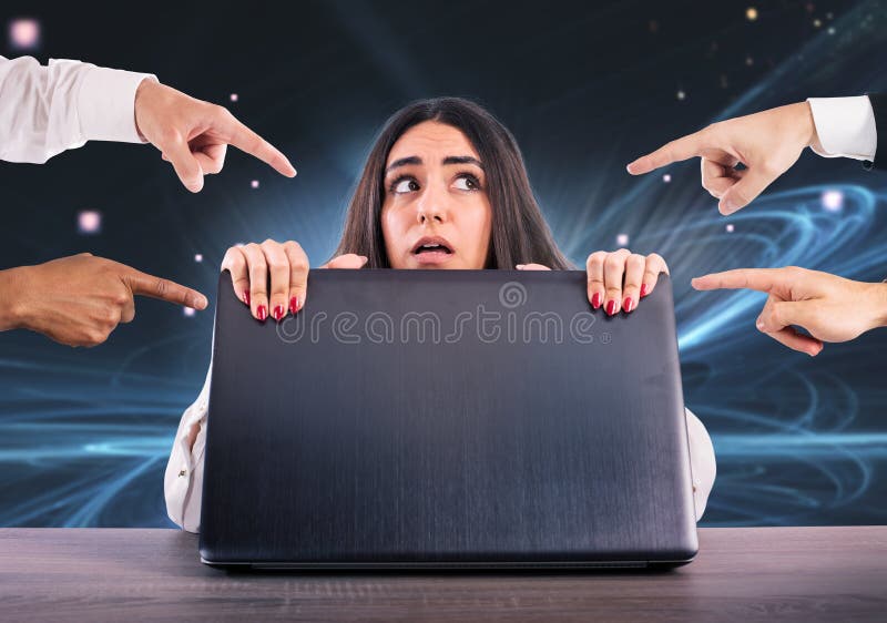 Afraid girl hides herself rear the laptop. She is victim of cyberbullying