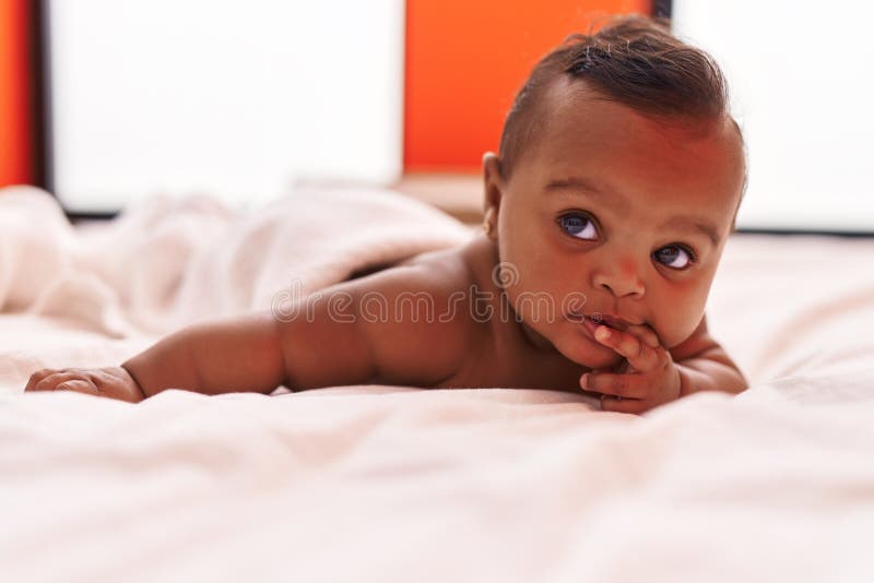 African American Baby Lying on Bed Having Legs Massage at Home Stock