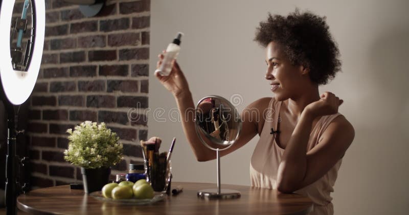 African american beauty vlogger pulvériser la lotion sur le visage clips vidéos