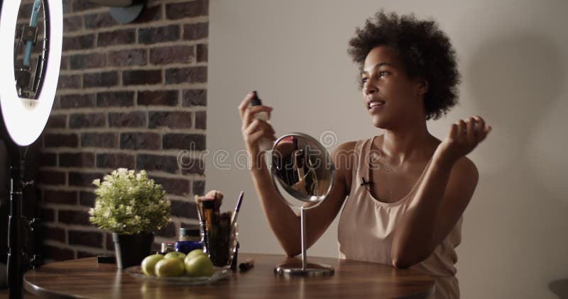 African american beauty vlogger pulvériser la lotion sur le visage clips vidéos