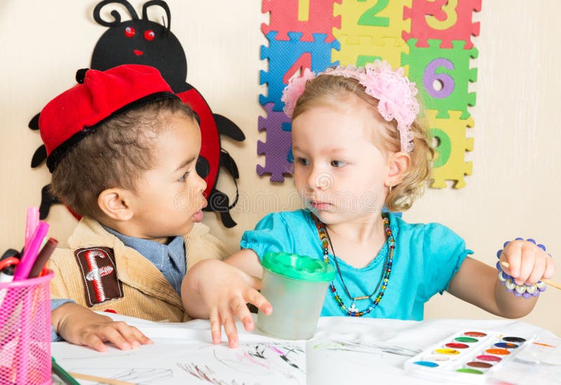 African American black boy and girl drawing with colorful pencils in preschool in kindergarten