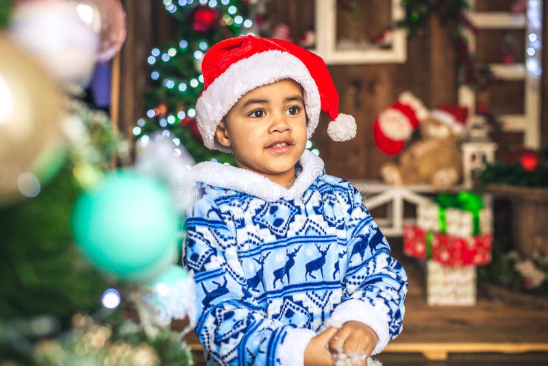 African American boy dressed costume Santa Claus decorating a Christmas tree. African American boy dressed costume Santa Claus Christmas tree decorated with toys royalty free stock images African American boy dressed costume Santa Claus decorating a Christmas tree. African American boy dressed costume Santa Claus Christmas tree decorated with toys royalty free stock images