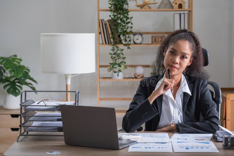 African American Businesswoman Working in the Office Using Laptops, Graphs and Office Equipment