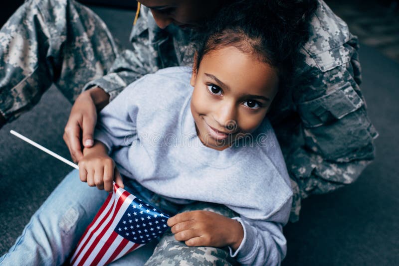 african american daughter and female soldier in military uniform with american flag