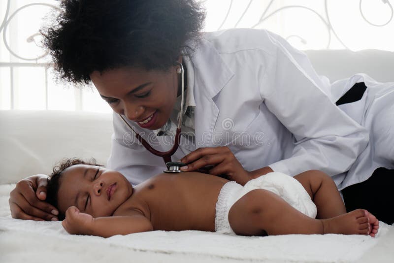 African american doctor examining black baby boy sleeping on bed with stethoscope
