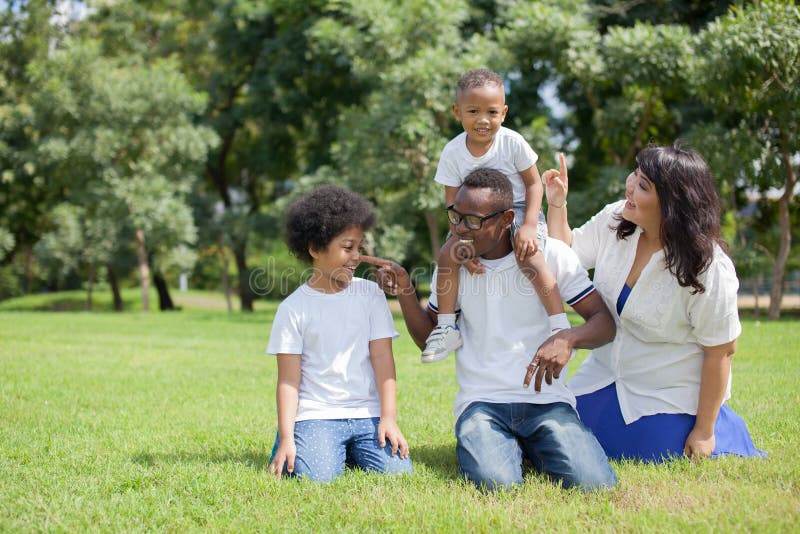 African American family alongside with Asian mum being playful and having good times in the park.