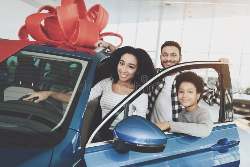 African american family at car dealership. Father, mother and son near new blue car.