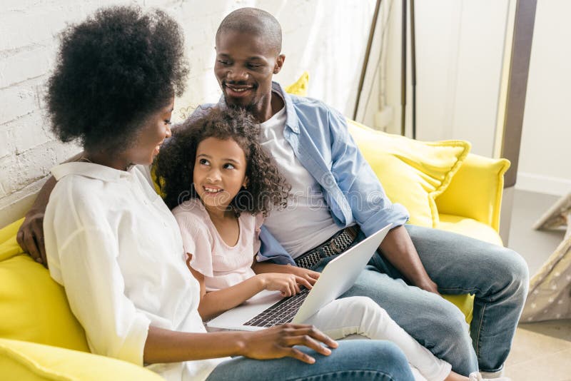 african american family with laptop resting on sofa together stock photography african american family with laptop resting on sofa together stock photography