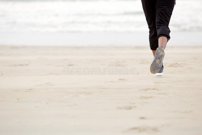 African american female running on beach with gym shoes