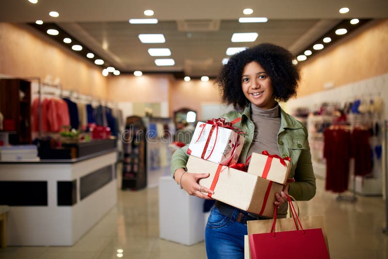 African american girl shopping gifts in mall on christmas sale. New year holidays concept. Smiling attractive mixed royalty free stock photo African american girl shopping gifts in mall on christmas sale. New year holidays concept. Smiling attractive mixed royalty free stock photo