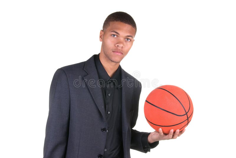 An African American basketball player holding a basketball while wearing his business casual suit. An African American basketball player holding a basketball while wearing his business casual suit