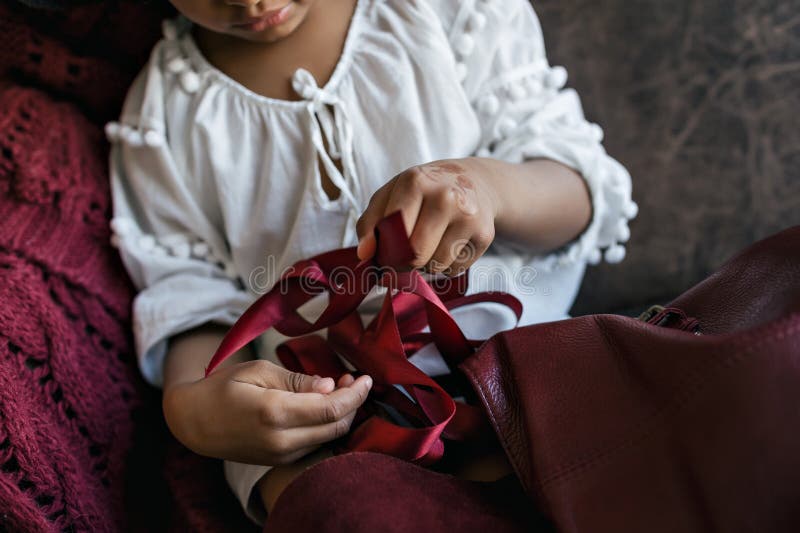 African american kid girl puts red satin ribbon in a red leather backpack royalty free stock photo