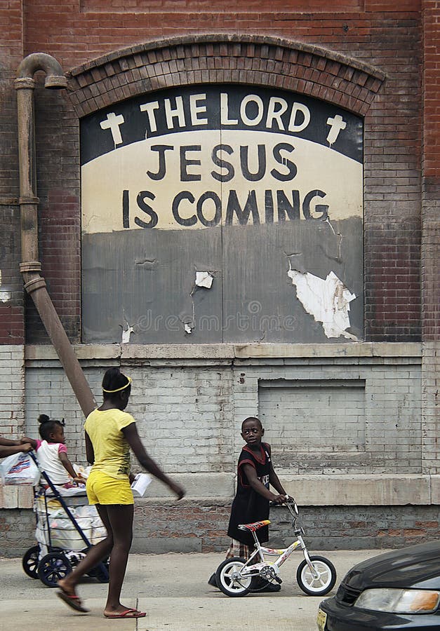 Three African American kids walk, ride in a cart and push a bicycle in front of a NYC building painted with the words The Lord Jesus is Coming. Three African American kids walk, ride in a cart and push a bicycle in front of a NYC building painted with the words The Lord Jesus is Coming.