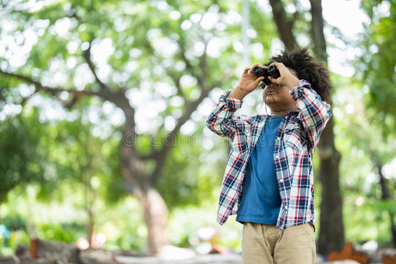 African American little boy with binoculars telescope looking birds in park on on holidays in summer stock image
