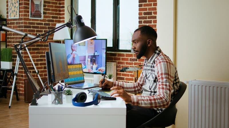 African american male designer edits images on dual monitors royalty free stock photography