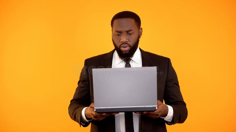 African-american male reading news on laptop and frowning, embarrassing news