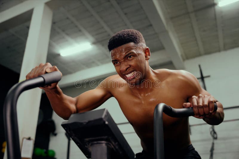 African American Male Using An Elliptical Trainer Doing Intense