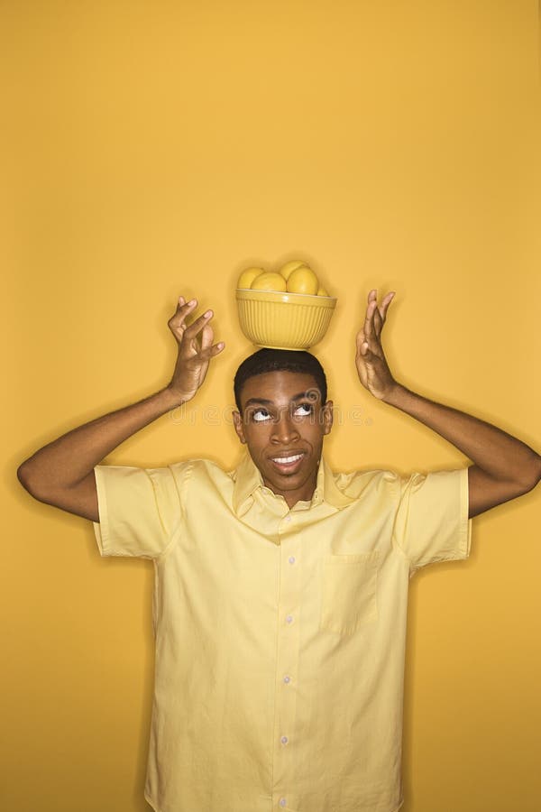 African-American man balancing bowl of lemons on his head. stock photos African-American man balancing bowl of lemons on his head. stock photos